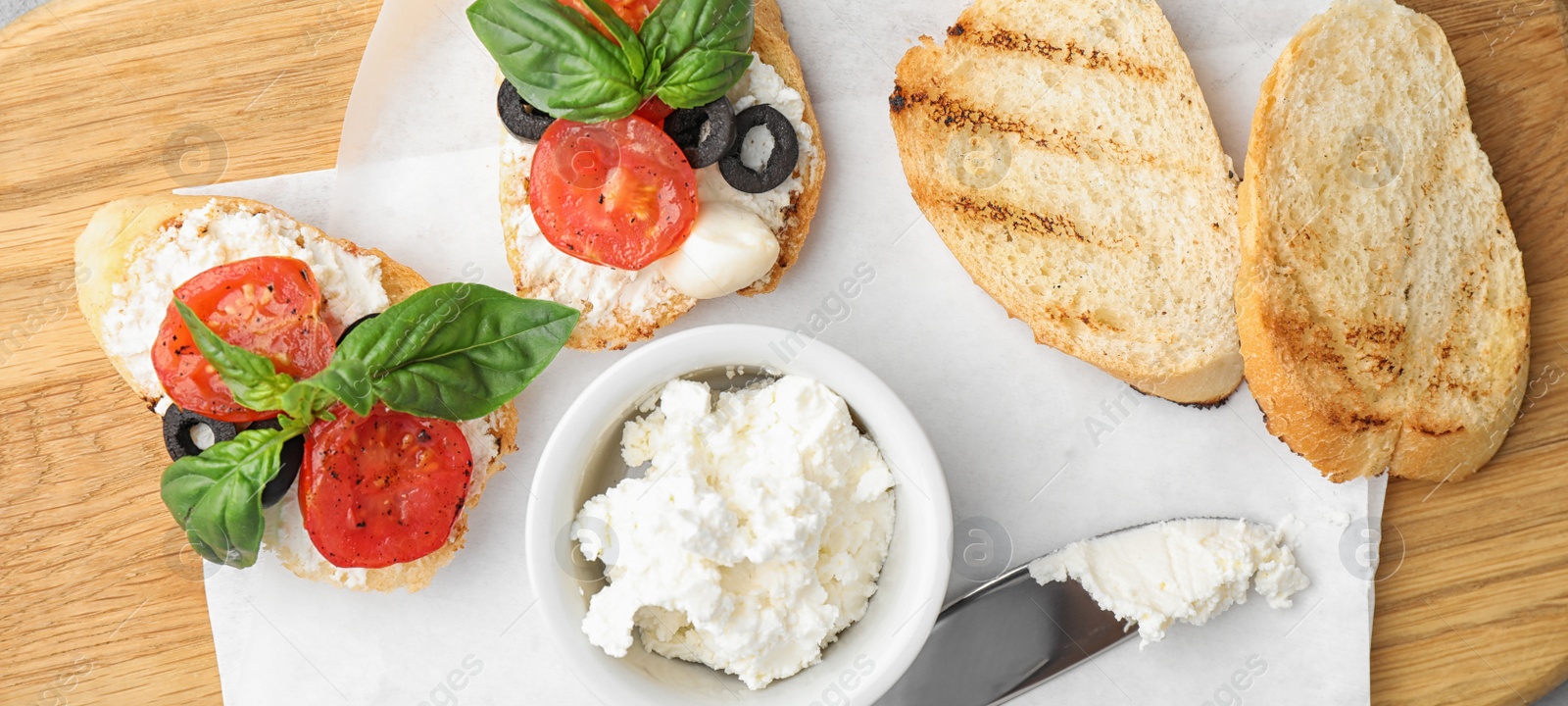 Image of Delicious tomato bruschettas on wooden board, top view. Banner design