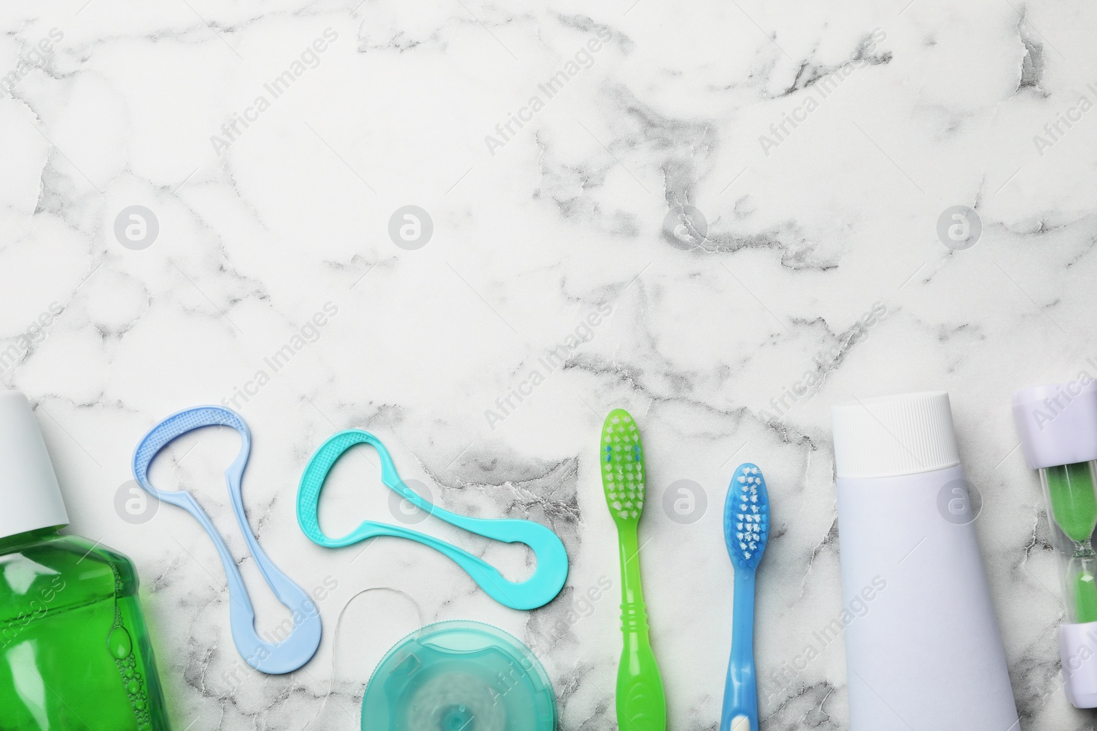 Photo of Flat lay composition with tongue cleaners and teeth care products on marble background. Space for text