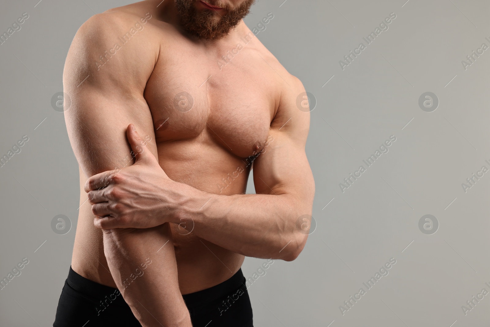 Photo of Man with muscular body on light grey background, closeup. Space for text