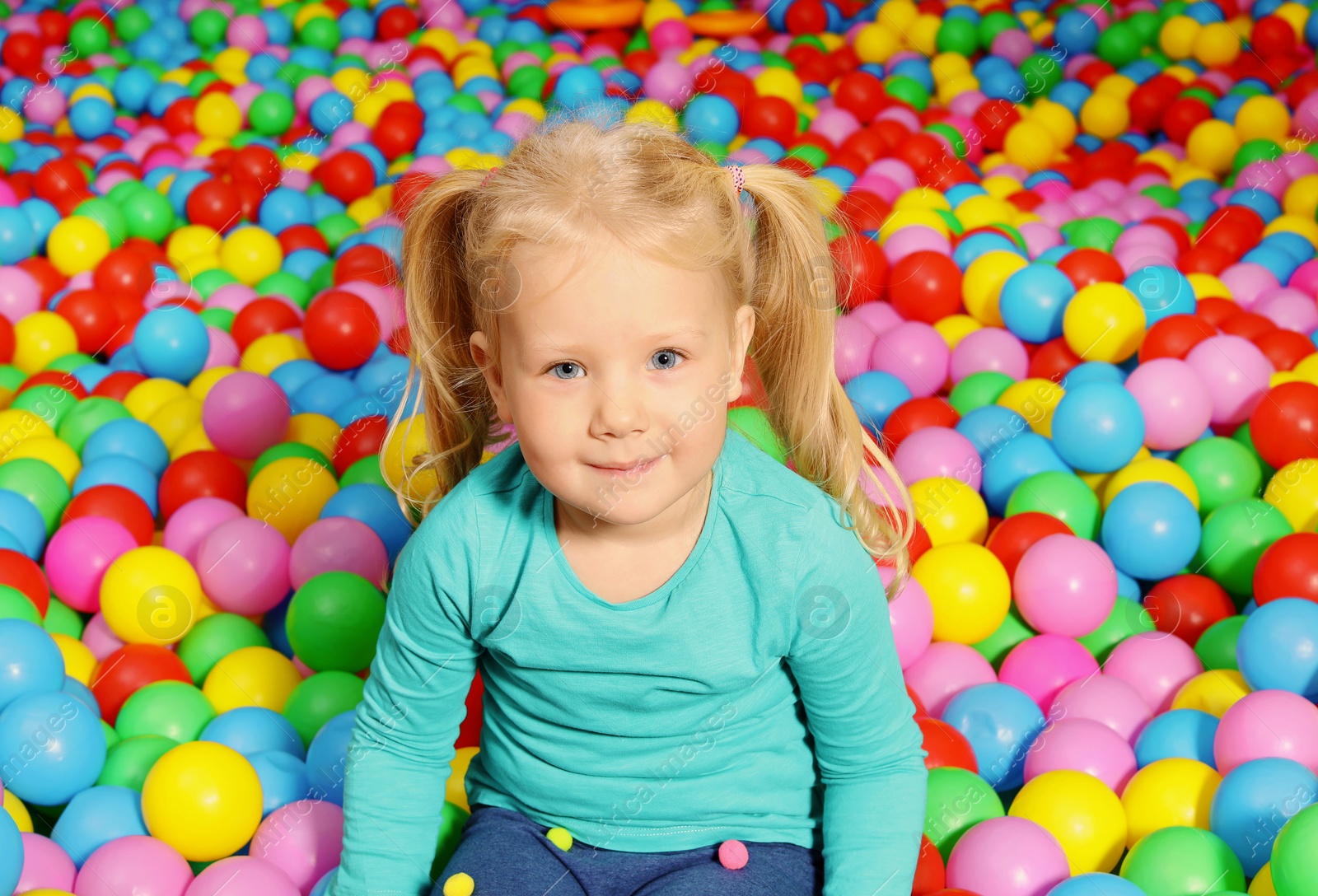 Photo of Cute child playing in ball pit indoors