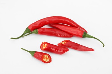 Photo of Whole and cut red hot chili peppers on white background