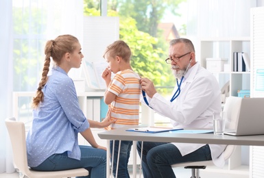 Photo of Coughing little boy with mother visiting doctor at clinic