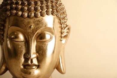 Photo of Beautiful golden Buddha sculpture on beige background, closeup. Space for text