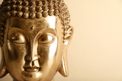 Beautiful golden Buddha sculpture on beige background, closeup. Space for text