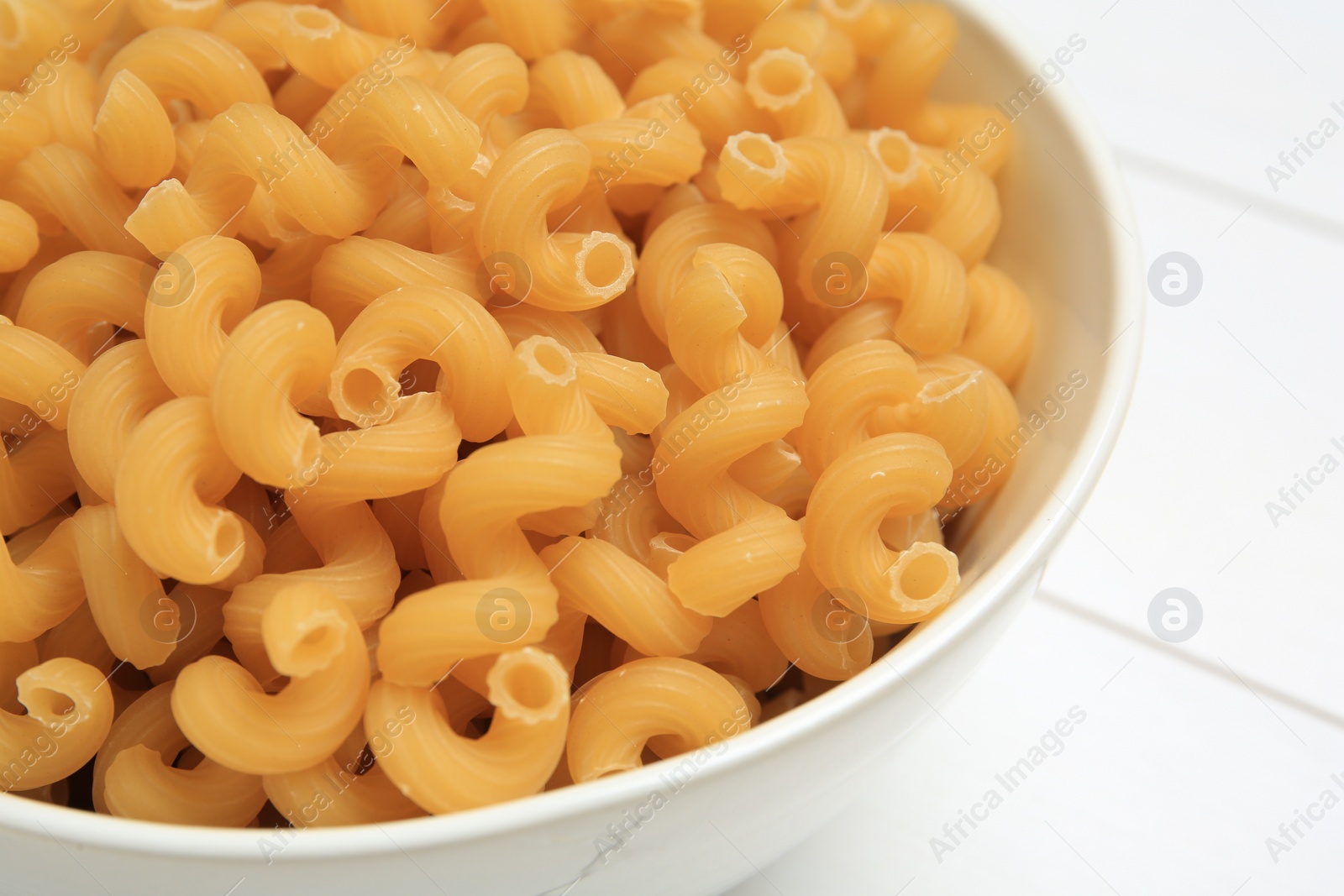 Photo of Raw cavatappi pasta in bowl on white table, closeup