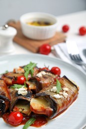 Photo of Delicious baked eggplant rolls with tomatoes, cheese and arugula on plate, closeup