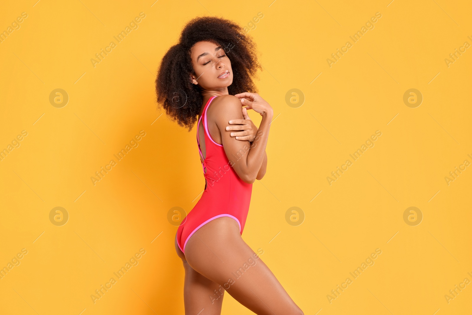 Photo of Beautiful woman in bright one-piece summer swimsuit on yellow background, space for text