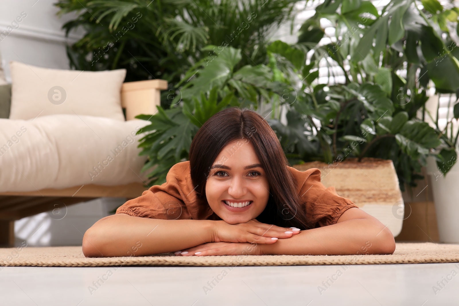 Photo of Beautiful woman lying on floor in living room decorated with houseplants. Interior design