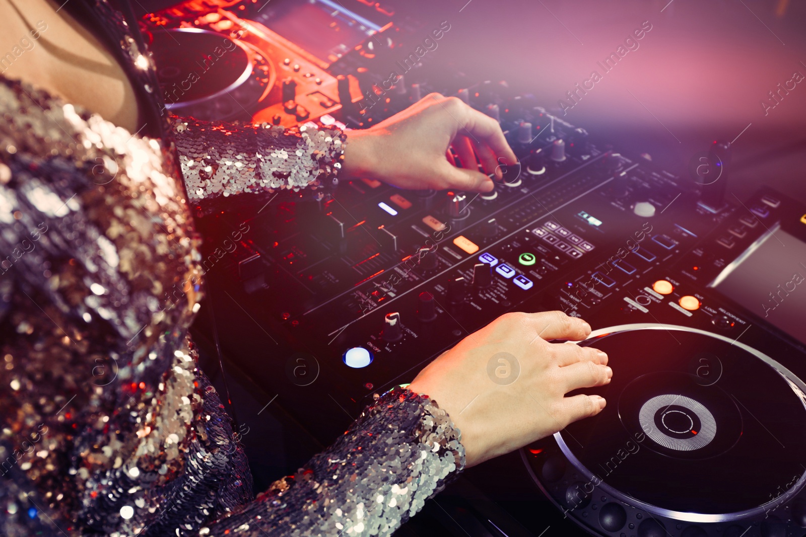 Photo of DJ creating music on modern console mixer in night club, closeup