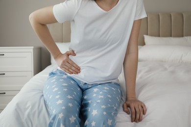 Photo of Woman suffering from appendicitis inflammation on bed at home, closeup