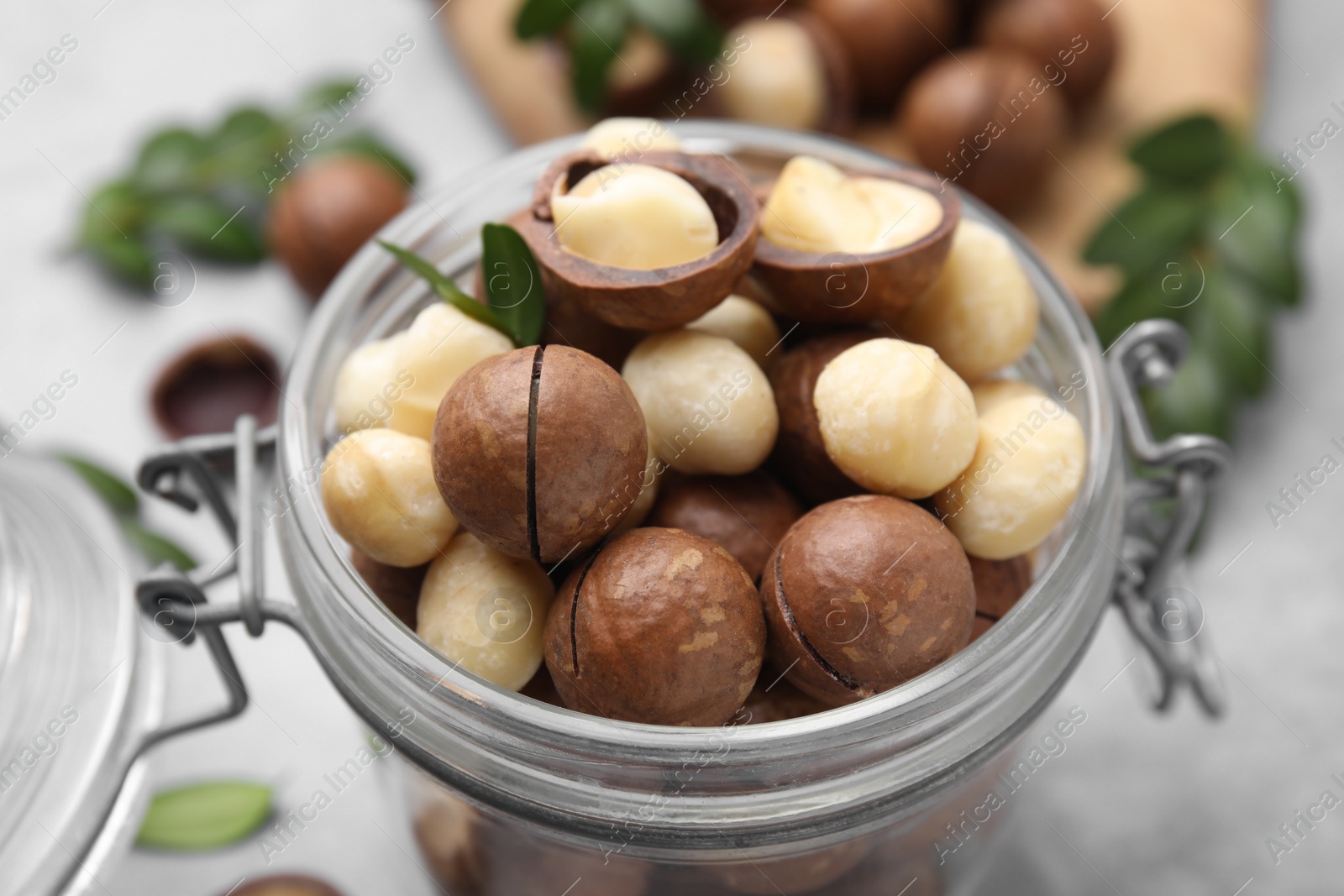 Photo of Tasty Macadamia nuts in jar on table, closeup