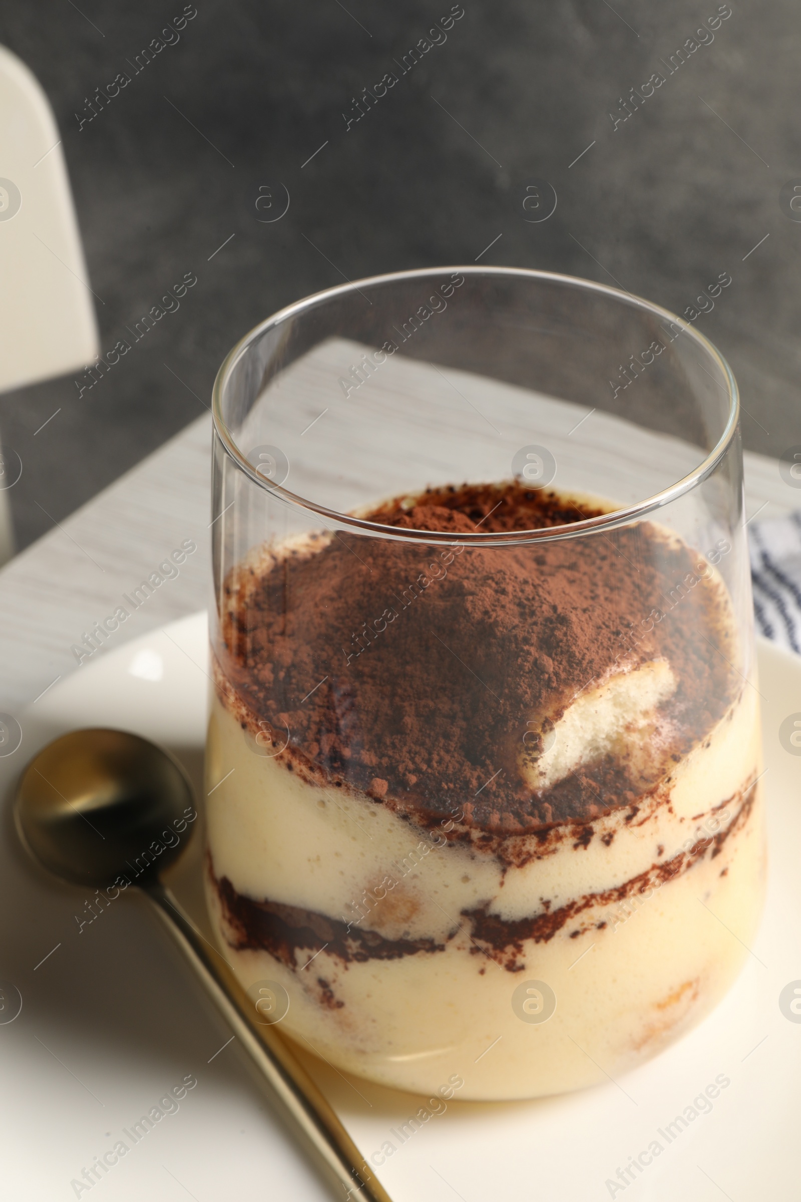 Photo of Delicious tiramisu in glass on table, closeup