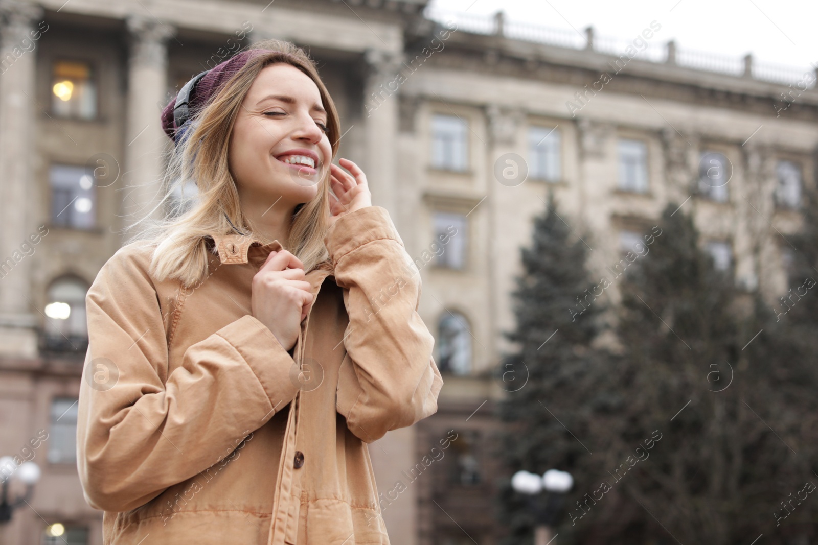 Photo of Young woman with headphones listening to music outdoors. Space for text