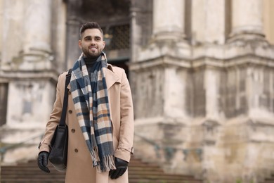 Smiling man in warm scarf outdoors. Space for text