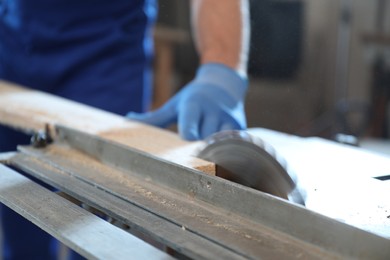 Photo of Professional carpenter working with wood in shop, closeup