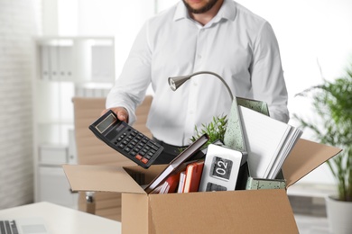 Photo of Young man packing stuff in box at office, closeup