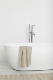 Photo of Beautiful white tub with towel in bathroom. Interior design