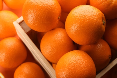 Photo of Fresh ripe oranges and wooden crate as background, closeup