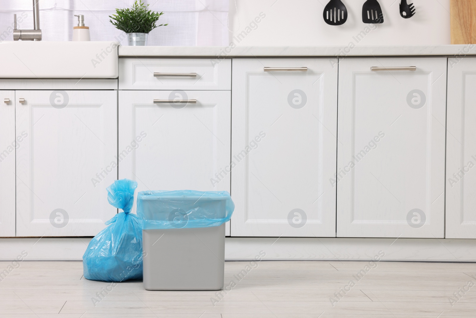 Photo of Plastic garbage bag and trash can in kitchen, space for text