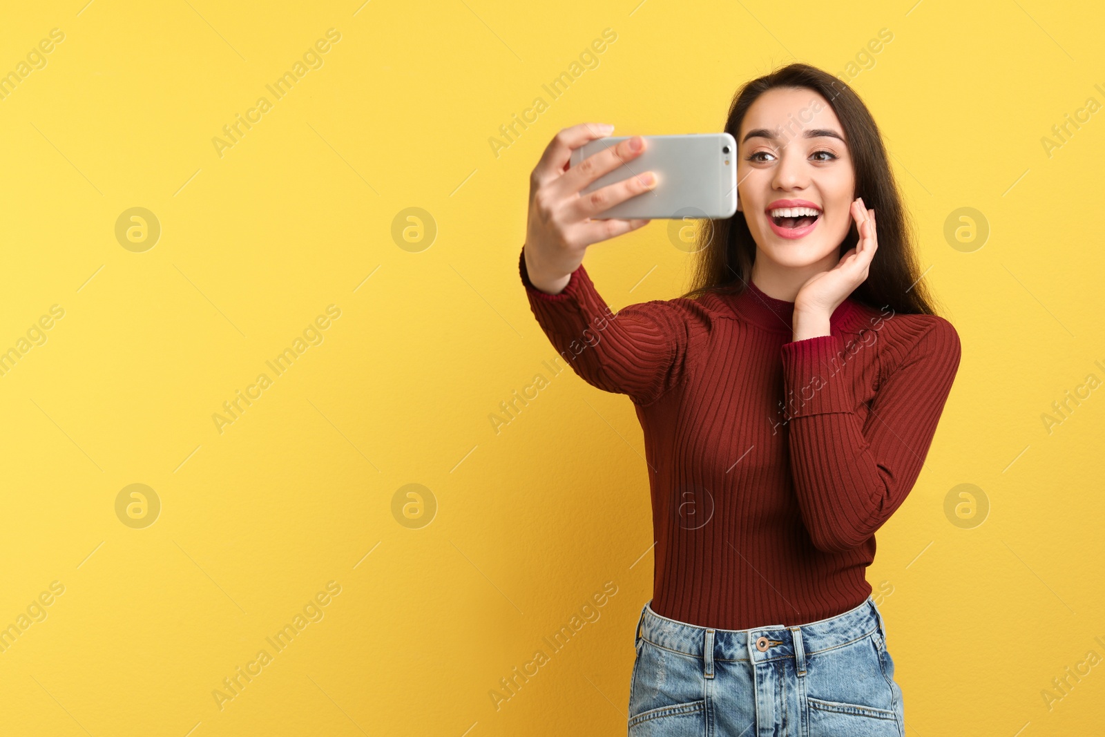 Photo of Attractive young woman taking selfie with phone on color background