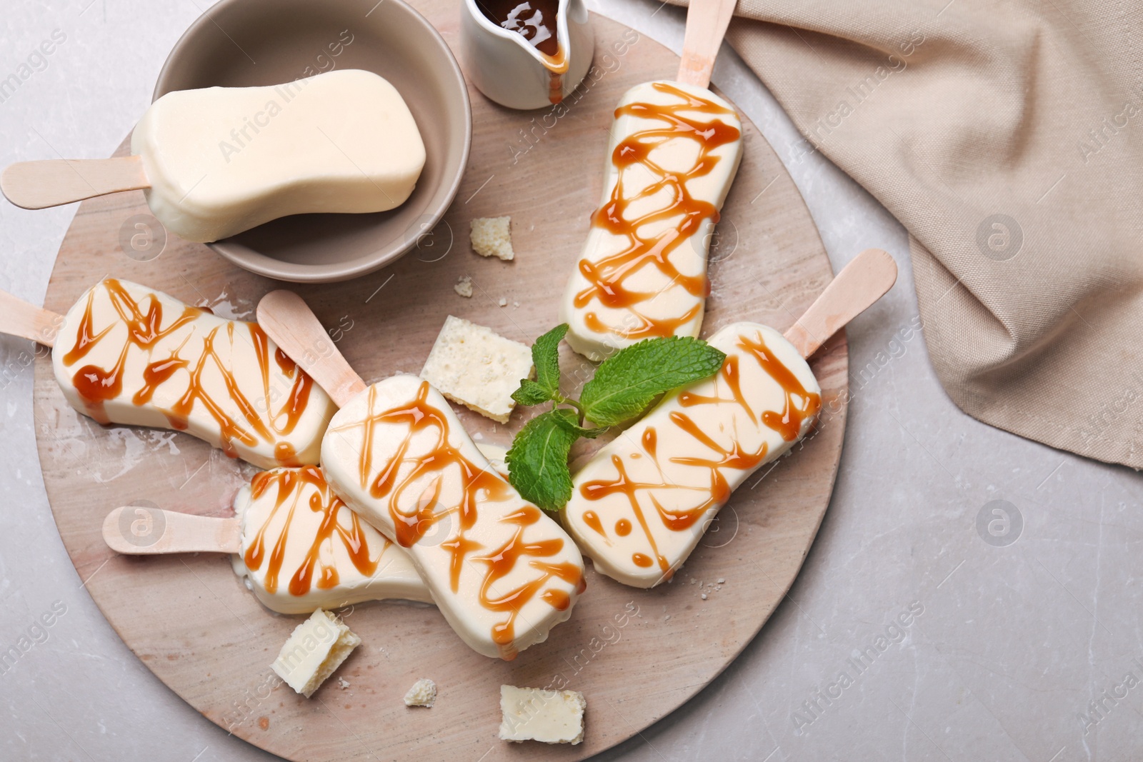 Photo of Delicious glazed ice cream bars, chocolate and mint on light grey marble table, flat lay