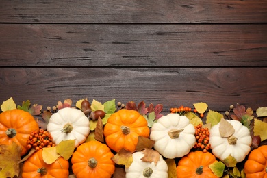 Flat lay composition with pumpkins and autumn leaves on wooden table. Space for text