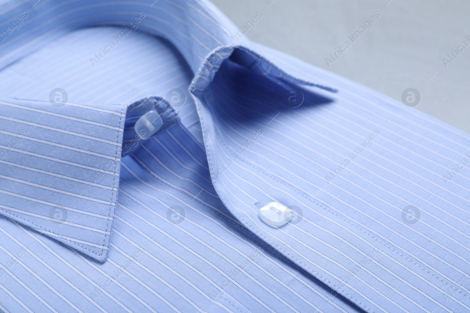 Photo of Closeup view of stylish light blue shirt. Dry-cleaning service