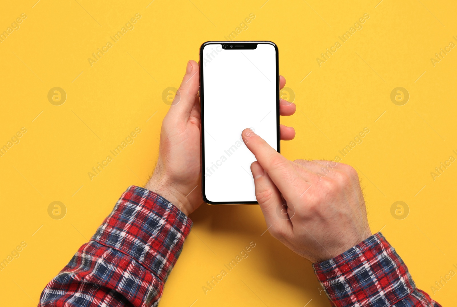 Photo of Man using smartphone on yellow background, closeup