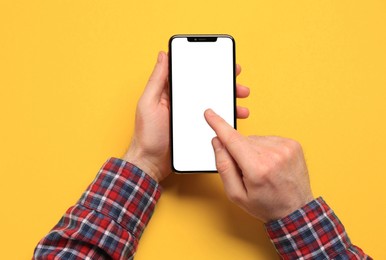 Photo of Man using smartphone on yellow background, closeup