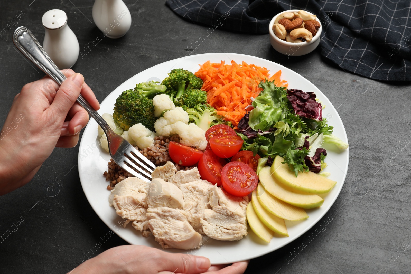 Photo of Balanced diet and healthy foods. Woman eating dinner at black table, closeup