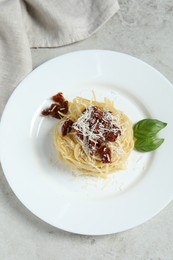 Photo of Tasty spaghetti with sun-dried tomatoes and parmesan cheese on white table, top view. Exquisite presentation of pasta dish