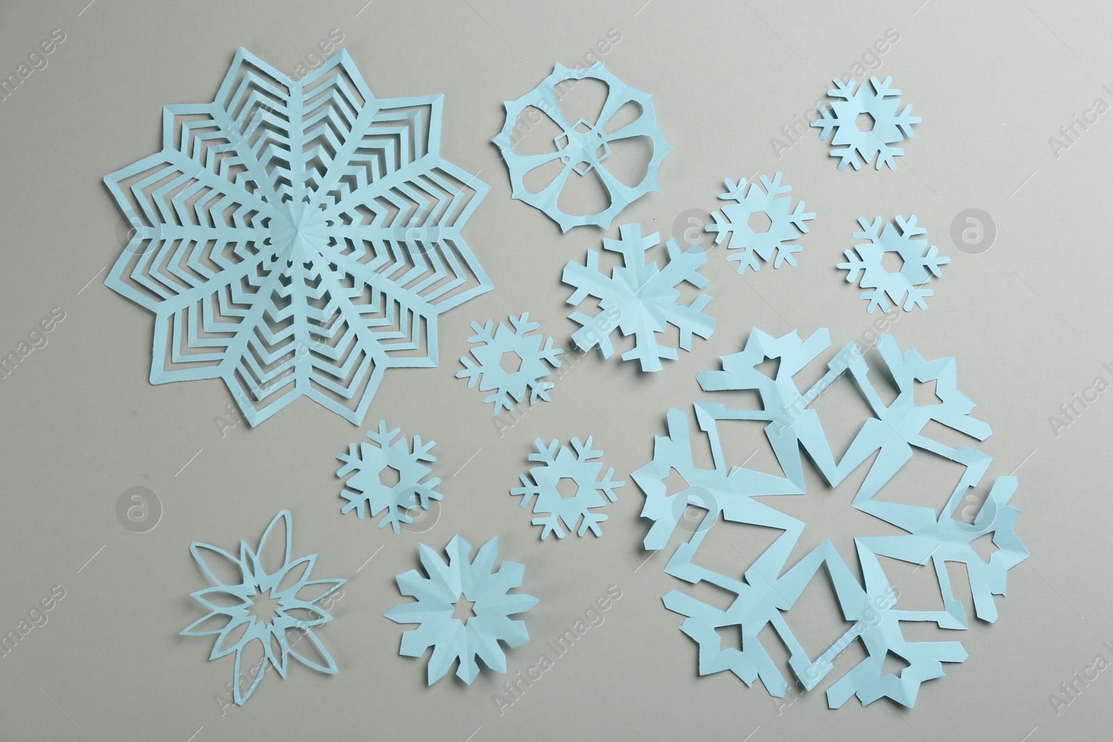Photo of Many paper snowflakes on light grey background, flat lay