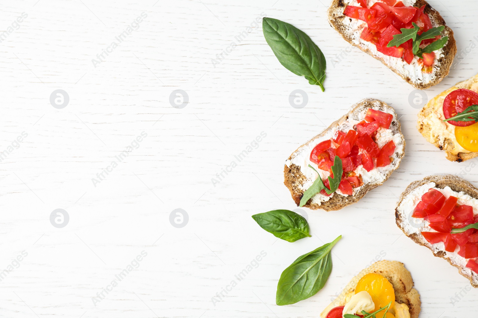 Photo of Delicious tomato bruschettas on white wooden background, flat lay. Space for text