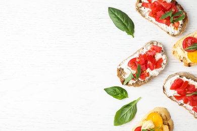 Photo of Delicious tomato bruschettas on white wooden background, flat lay. Space for text