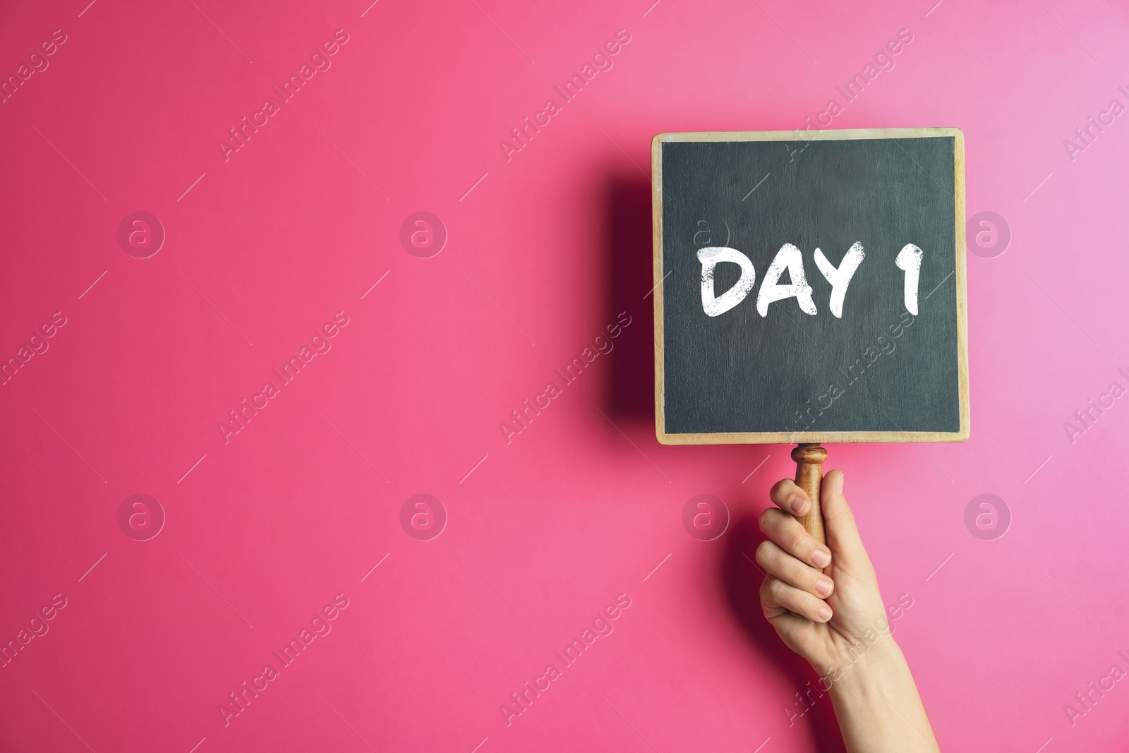 Image of Starting new life. Woman holding blackboard with text Day 1 on pink background, closeup. Space for text