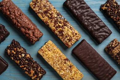 Different tasty protein bars on light blue wooden table, flat lay