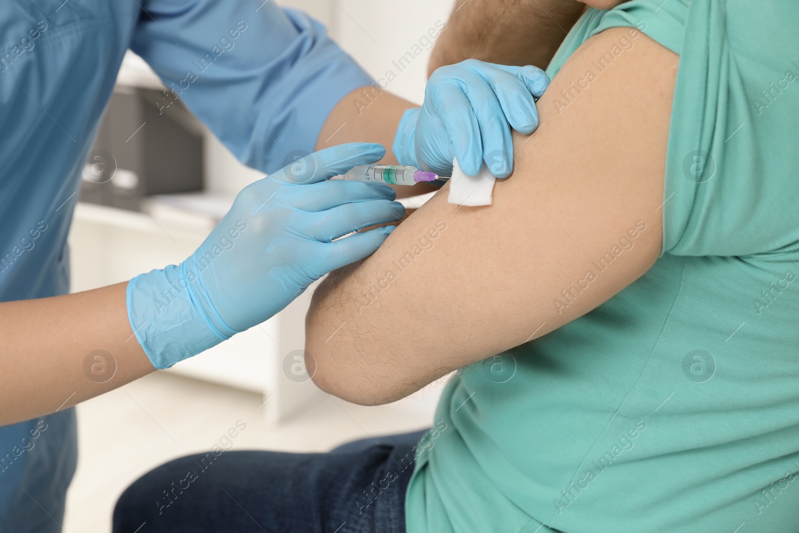 Photo of Doctor giving hepatitis vaccine to patient in clinic, closeup