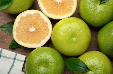 Photo of Whole and cut sweetie fruits on wooden table, flat lay