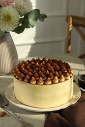 Photo of Delicious tiramisu cake with cocoa powder served on light table indoors
