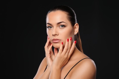 Photo of Portrait of beautiful young woman with bright manicure on black background. Nail polish trends