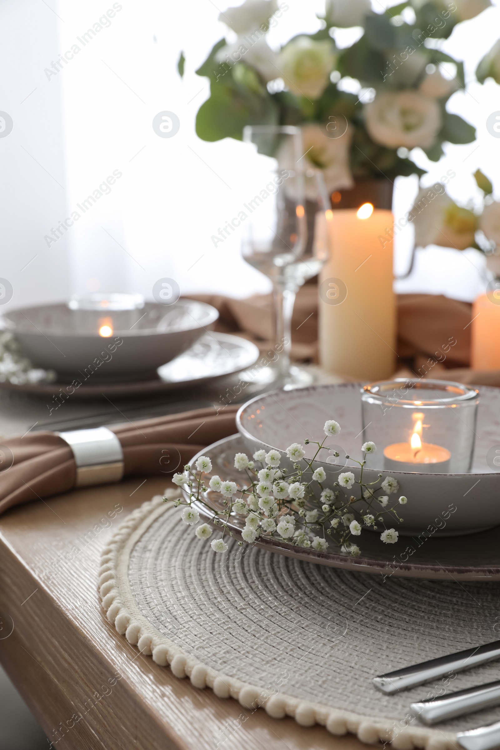 Photo of Festive table setting with beautiful candles and floral decor in restaurant, closeup