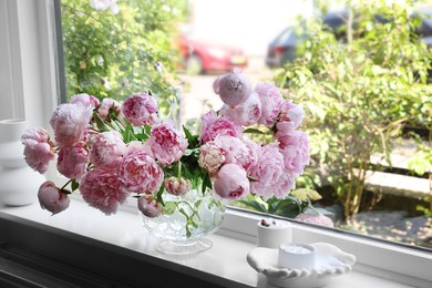 Beautiful pink peonies in vase on window sill. Interior design