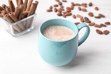 Mug with delicious hot cocoa drink and cookies on table