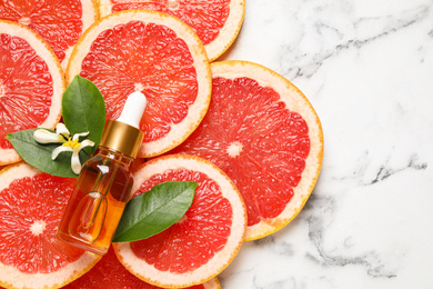 Flat lay composition with bottle of citrus essential oil on white marble background