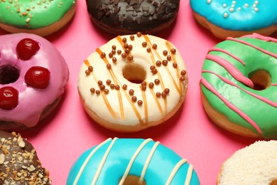 Photo of Different delicious glazed doughnuts on pink background, closeup