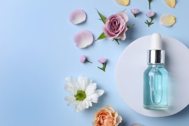 Photo of Bottle of cosmetic serum, beautiful flowers and petals on light blue background, flat lay. Space for text