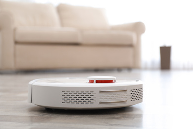 Photo of Modern robotic vacuum cleaner on floor in living room. Space for text