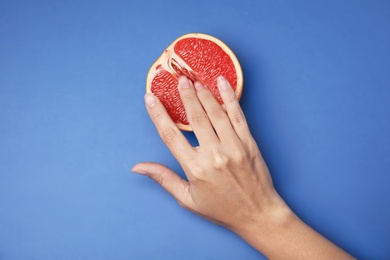 Photo of Young woman touching half of grapefruit on blue background, top view. Sex concept