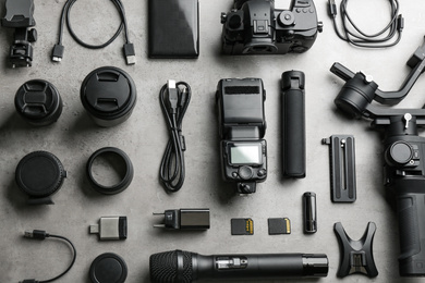 Flat lay composition with camera and video production equipment on light grey stone background