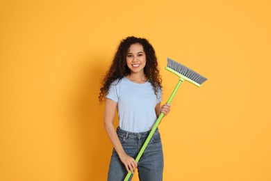 African American woman with green broom on orange background